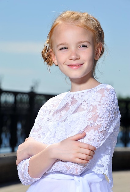 Imagen de una niña con vestido blanco posando al aire libre