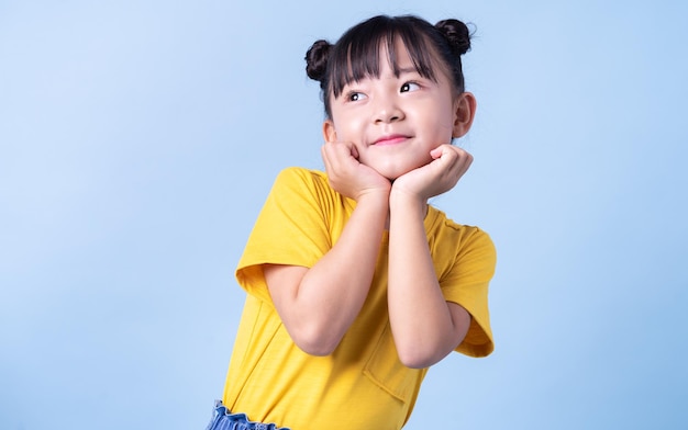 Imagen de niño asiático posando sobre fondo azul.