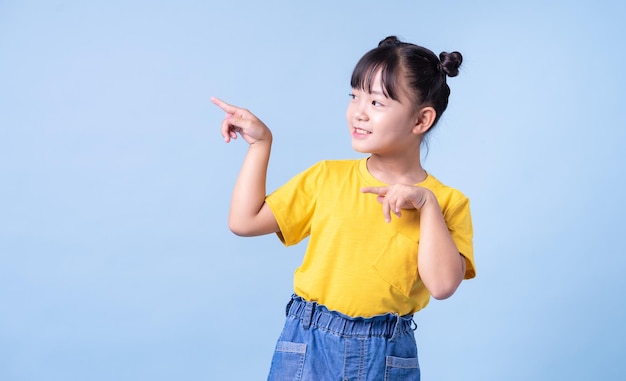 Imagen de niño asiático posando sobre fondo azul.