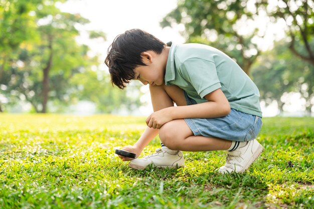 Imagen de un niño asiático usando una lupa en un parque