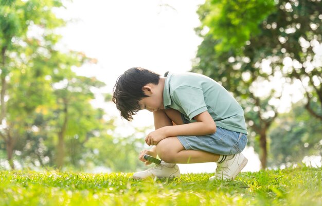 Imagen de un niño asiático usando una lupa en un parque