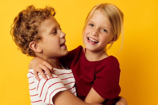 Imagen de niño y niña positivos abrazando entretenimiento infantil de moda sobre fondo de color