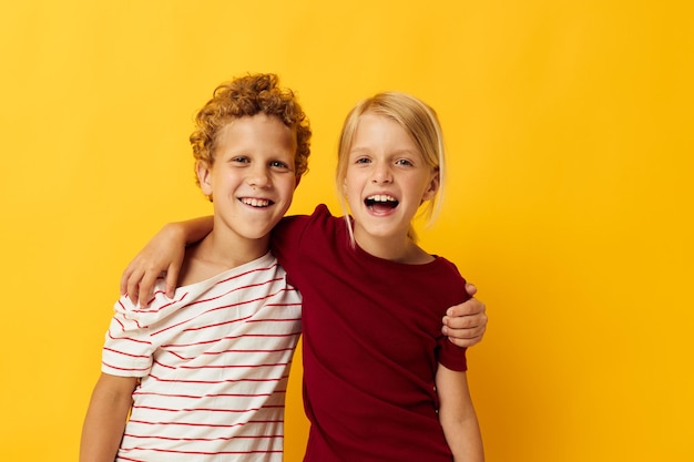 Imagen de un niño y una niña positivos parados uno al lado del otro posando emociones infantiles fondo amarillo