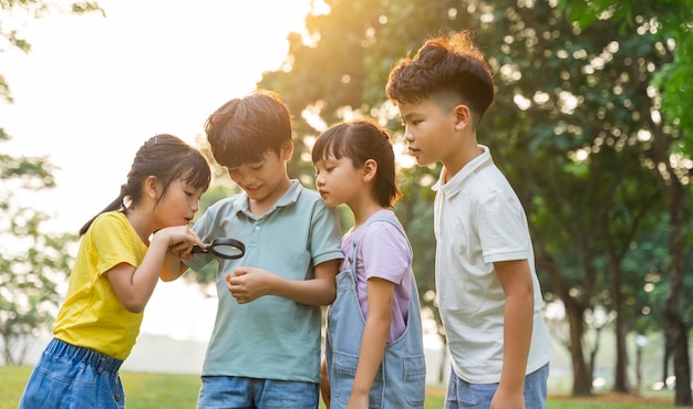 Imagen de niños asiáticos usando una lupa en el parque