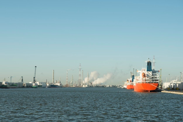 Imagen panorámica de la petroquímica en el puerto de Amberes con barcos amarrados y vapor saliendo de las chimeneas