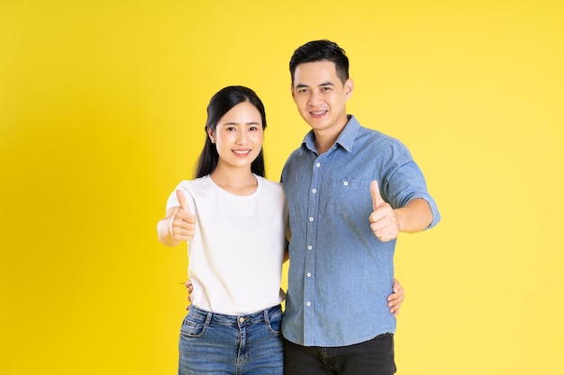 Imagen de pareja asiática posando sobre fondo amarillo