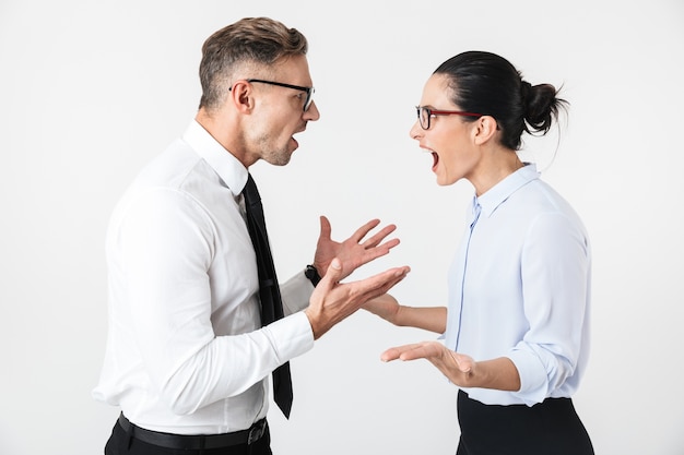 Foto imagen de pareja de colegas de negocios enojados jóvenes aislados sobre pared blanca hablando entre sí.