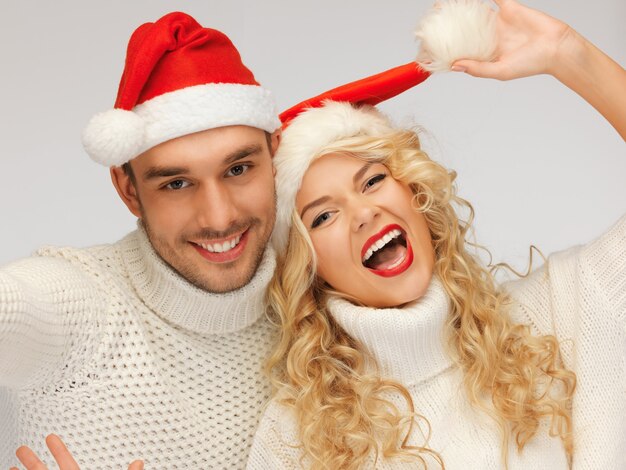 imagen de la pareja de la familia en suéteres y sombreros de santa