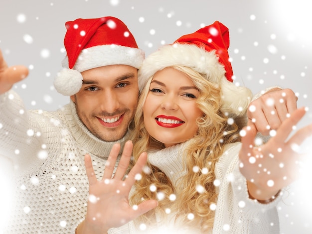 imagen de la pareja de la familia en suéteres y sombreros de santa