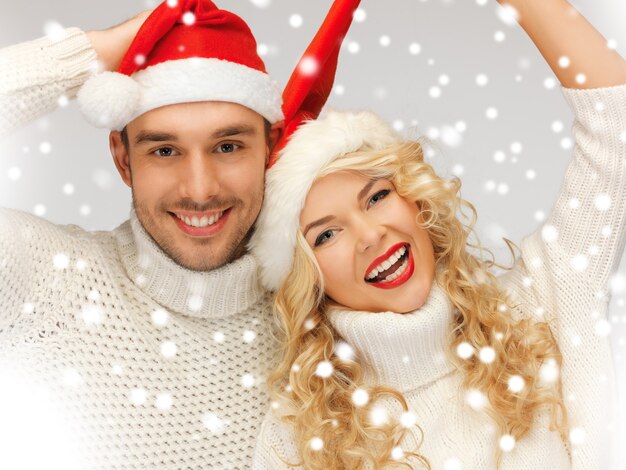 imagen de la pareja de la familia en suéteres y sombreros de santa