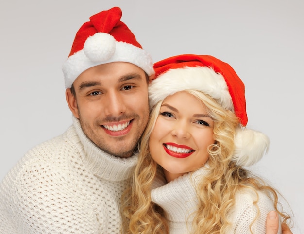 imagen de la pareja de la familia en suéteres y sombreros de santa