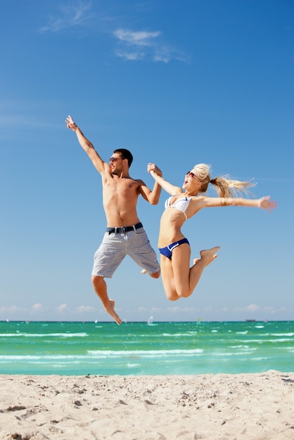 imagen de una pareja feliz saltando en la playa (centrarse en el hombre).