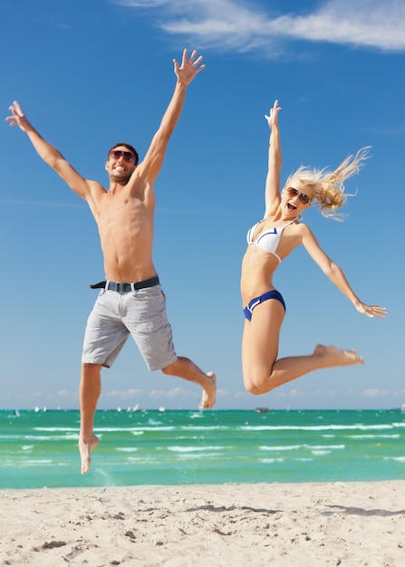 imagen de pareja feliz saltando en la playa