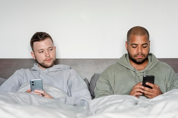Imagen de pareja gay enojada, en sus teléfonos después de discutir