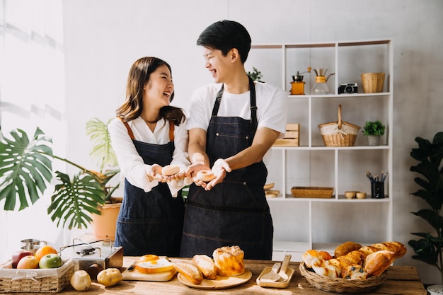 Imagen de una pareja de recién casados cocinando en casa Una pareja joven de Asia cocinando juntos con pan y fruta en una cocina acogedora en casa