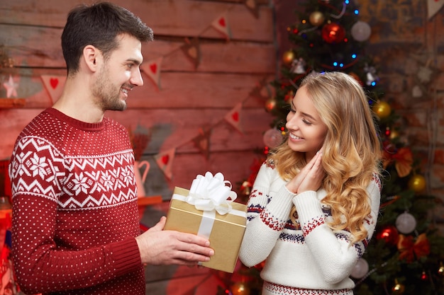 Imagen de pareja romántica en un suéter con caja de regalo