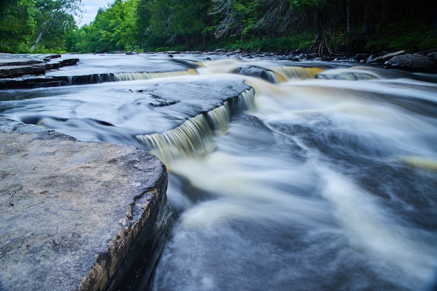 Imagen de pequeñas cascadas sobre rocas grises en el bosque