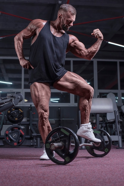 Imagen de un poderoso atleta posando en el gimnasio. Concepto de fitness y culturismo. Técnica mixta