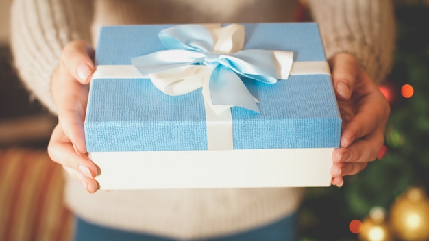 Imagen de portarretrato de tonos de la caja de regalo de Navidad de mujer joven que lo muestra en la cámara. Imagen perfecta para fiestas de invierno y celebraciones.