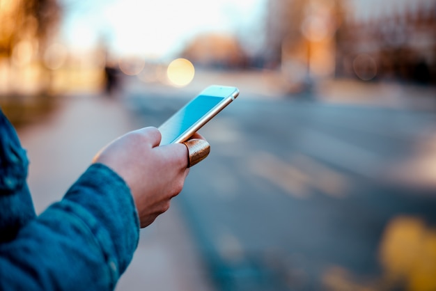 Imagen del primer de una mano femenina usando el teléfono en la calle de la ciudad.