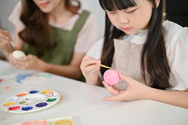 Imagen de primer plano Una adorable joven asiática se centra en pintar un huevo de Pascua