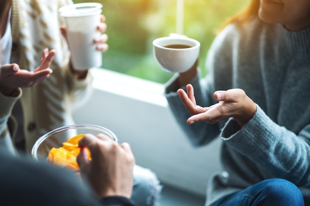 Imagen de primer plano de amigos hablando bebiendo y comiendo papas fritas juntos