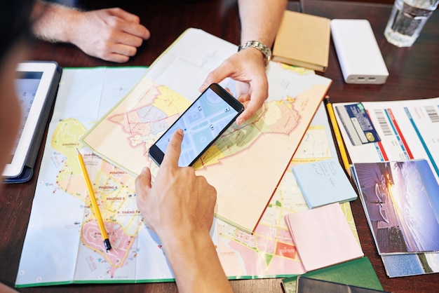 Imagen de primer plano de amigos que verifican el mapa en el teléfono inteligente al planificar un viaje por carretera al mar