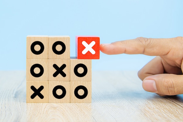 Imagen de primer plano de bloques de juguete de madera en forma de cubo recogidos a mano con el símbolo X apilados para la gestión empresarial y la estrategia de conceptos de éxito