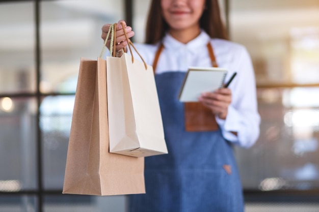 Imagen de primer plano de una camarera empresaria sosteniendo y dando una bolsa de compras al cliente