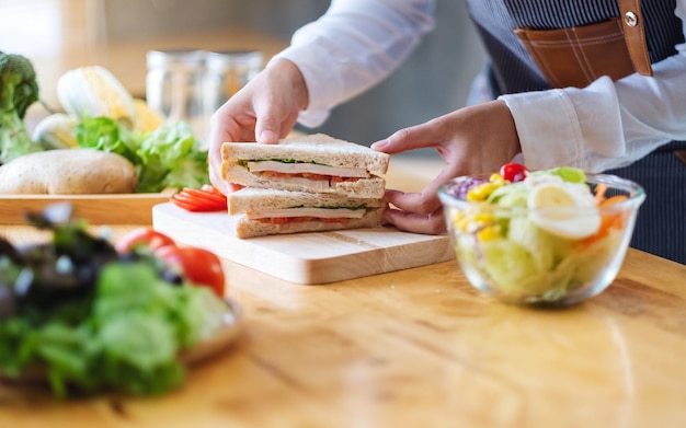 Foto imagen de primer plano de un chef cocinando sándwich de trigo integral y ensalada de verduras en la cocina