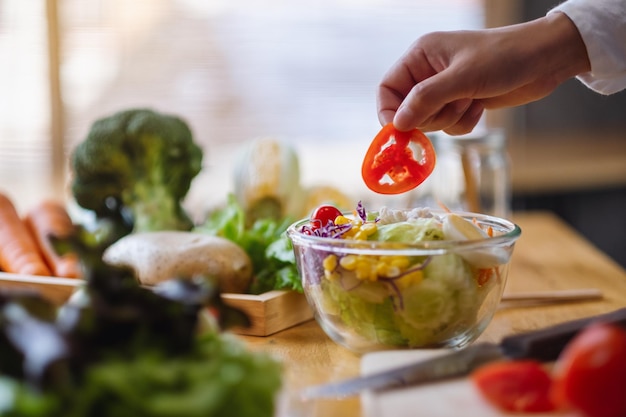 Foto imagen de primer plano de una cocinera cocinando una ensalada de verduras mixtas frescas en la cocina