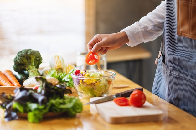 Imagen de primer plano de una cocinera cocinando una ensalada de verduras mixtas frescas en la cocina