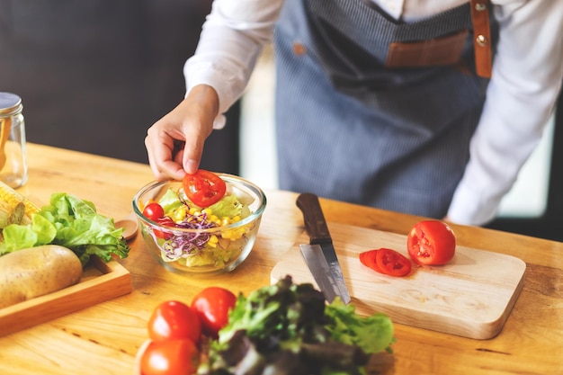 Imagen de primer plano de una cocinera cocinando una ensalada de verduras mixtas frescas en la cocina