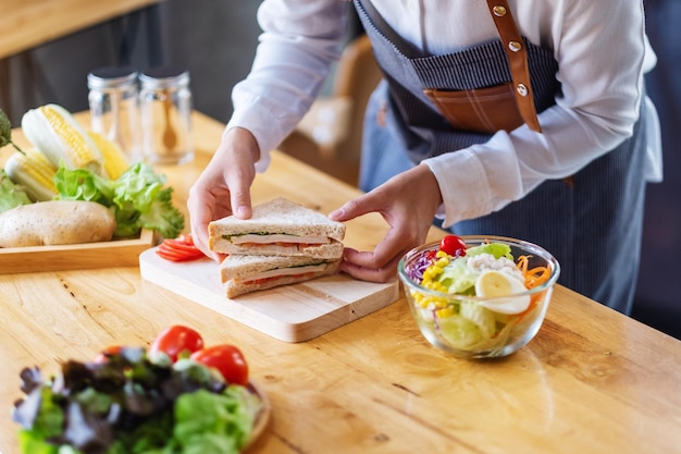 Imagen de primer plano de una cocinera cocinando y sosteniendo un trozo de sándwich de trigo integral en la cocina