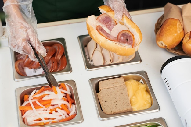 Imagen de primer plano del cocinero agregando cebolla y zanahoria en sándwich para que el cliente vea desde arriba