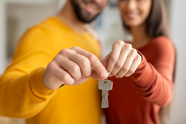 Imagen de primer plano del concepto de bienes raíces de una pareja joven con las llaves de la casa