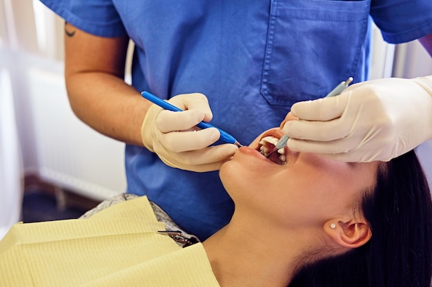 Imagen de primer plano de un dentista que examina los dientes de una mujer en odontología.