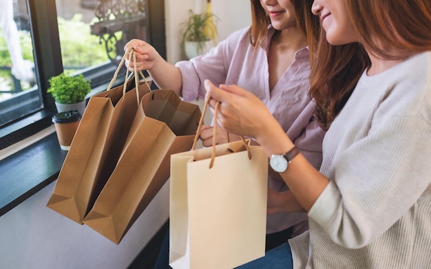 Imagen de primer plano de dos mujeres jóvenes abriendo y mirando bolsas de compras juntas