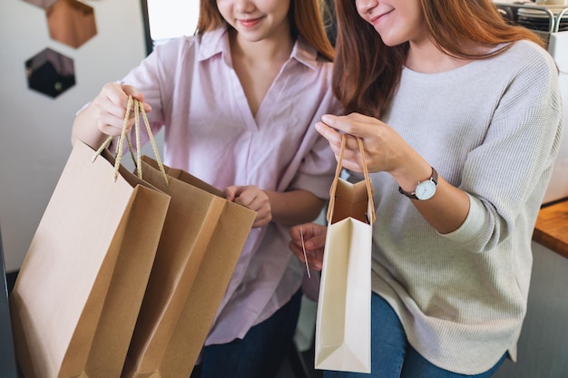 Foto imagen de primer plano de dos mujeres jóvenes abriendo y mirando bolsas de compras juntas