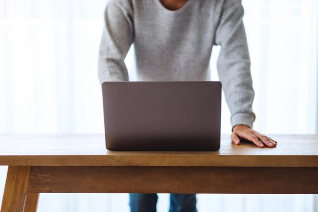 Imagen de primer plano de un empresario trabajando y usando una computadora portátil en una mesa de madera