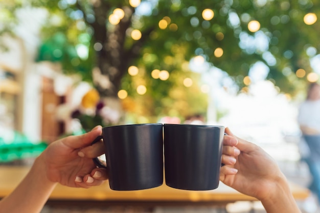 Imagen de primer plano de una gente que tintinea tazas de café juntas en el café
