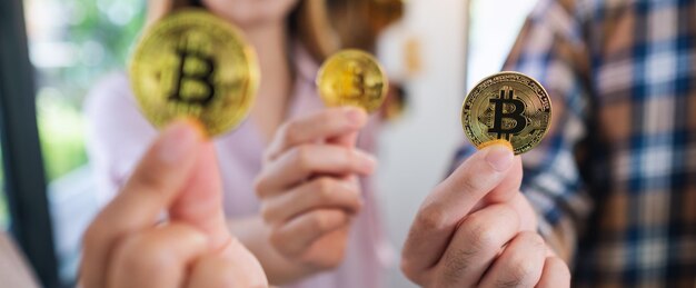 Imagen de primer plano de un grupo de personas sosteniendo y mostrando bitcoins de color dorado en las manos