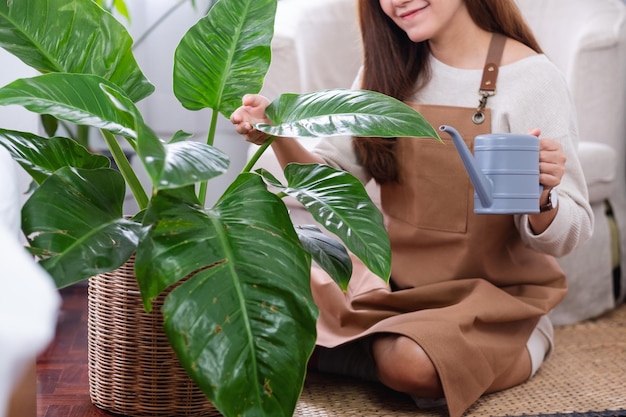 Imagen de primer plano de una hermosa joven asiática cuidando y regando las plantas de interior con una lata de agua en casa