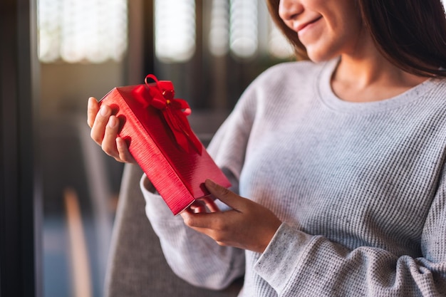 Imagen de primer plano de una hermosa joven asiática sosteniendo una caja de regalo roja