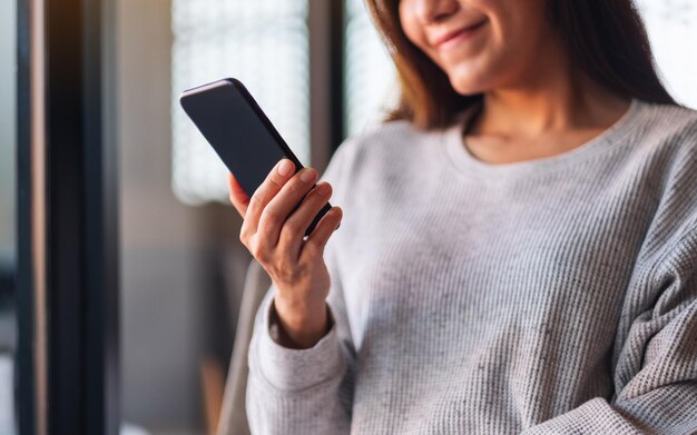 Imagen de primer plano de una hermosa joven asiática sosteniendo y usando un teléfono móvil