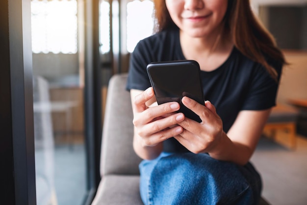 Imagen de primer plano de una hermosa joven asiática sosteniendo y usando un teléfono móvil