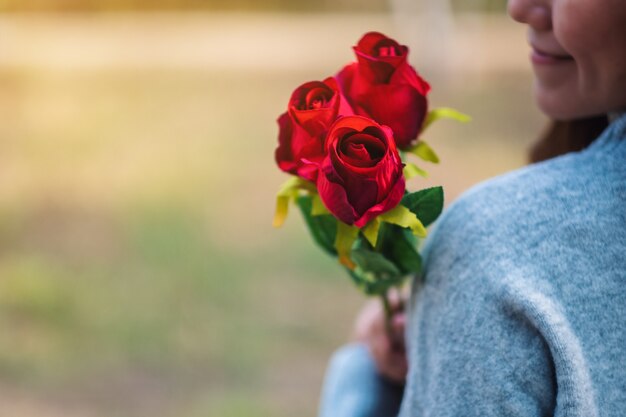 Imagen de primer plano de una hermosa mujer asiática sosteniendo flores de rosas rojas con sentirse feliz en el día de San Valentín