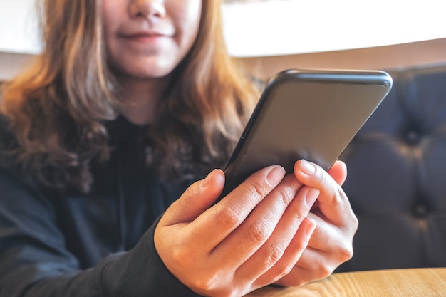 Imagen de primer plano de una hermosa mujer asiática sosteniendo, usando y mirando el teléfono inteligente con sentirse feliz