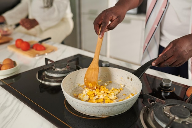 Imagen de primer plano del hombre cocinando huevos revueltos para el desayuno familiar