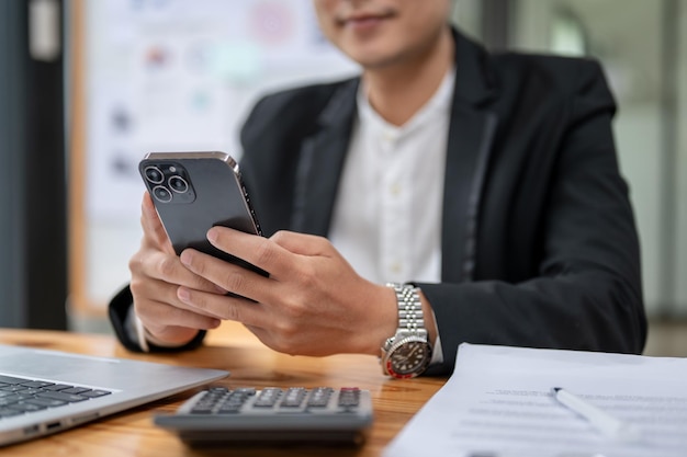 Imagen de primer plano de un hombre de negocios que usa su teléfono inteligente en su escritorio, chat de texto, aplicaciones de correo electrónico SMS